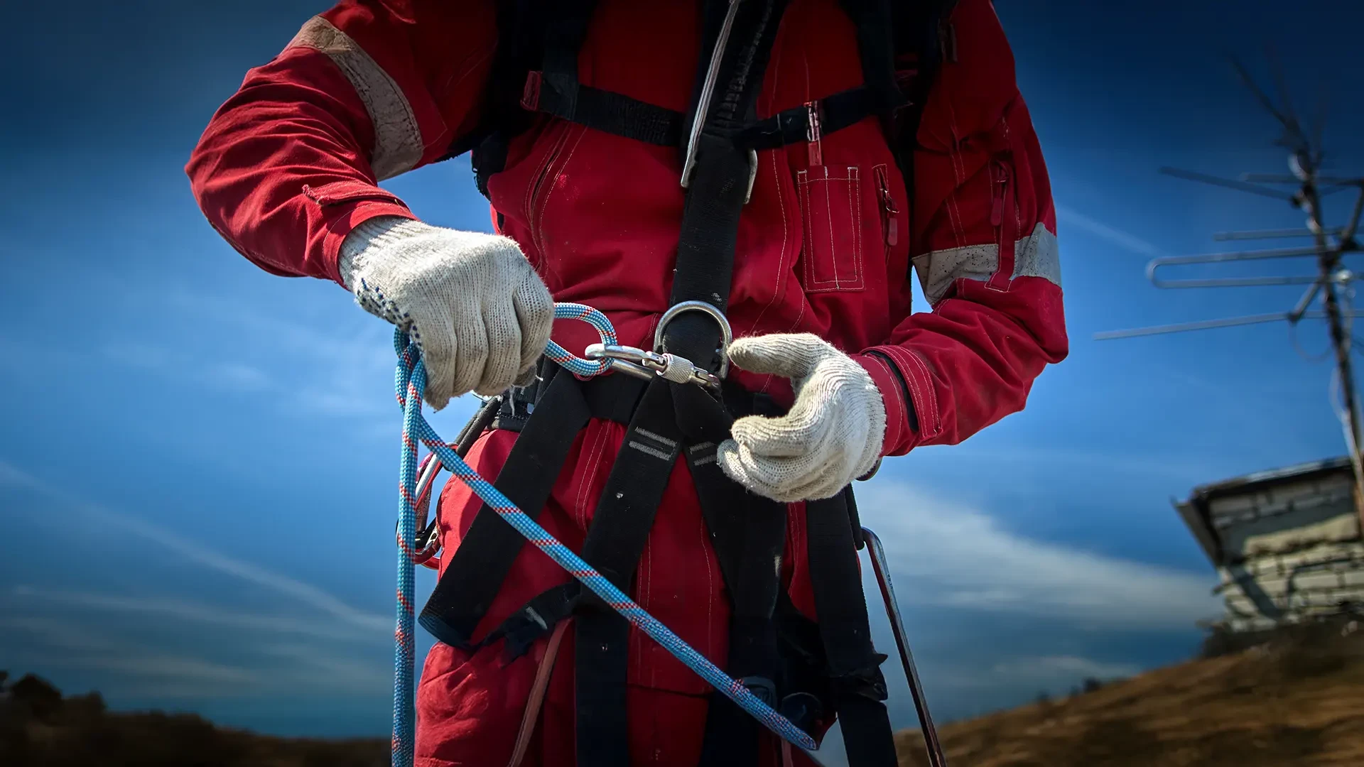 Un ouvrier du bâtiment, portant des gants et une ceinture d'outils, soulève des poutres en bois tout en naviguant à travers un espace intérieur partiellement construit