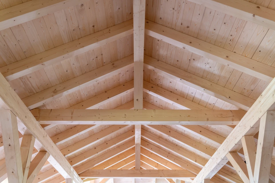 Structure de charpente en bois en cours de construction sous ciel bleu, vue depuis l'intérieur