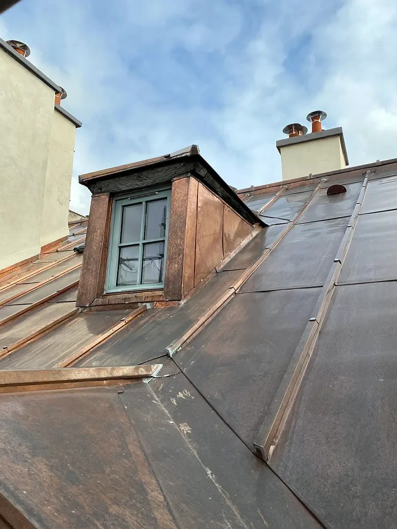 Toiture moderne en t&ocirc;le nervur&eacute;e m&eacute;tallique verte, vue en contre-plong&eacute;e sur angle de b&acirc;timent r&eacute;sidentiel