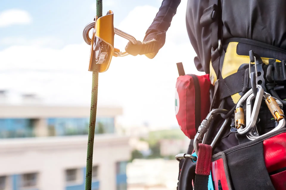 Chantier ext&eacute;rieur avec trois ouvriers &eacute;quip&eacute;s de harnais de s&eacute;curit&eacute; rouge travaillant sur &eacute;chafaudage m&eacute;tallique
