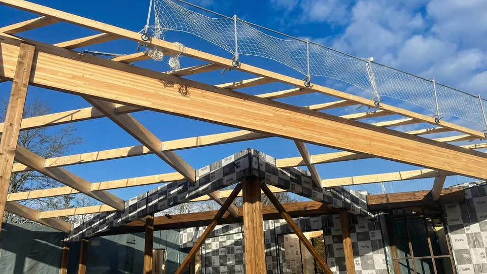 Structure de charpente en bois en cours de construction sous ciel bleu, vue depuis l'intérieur