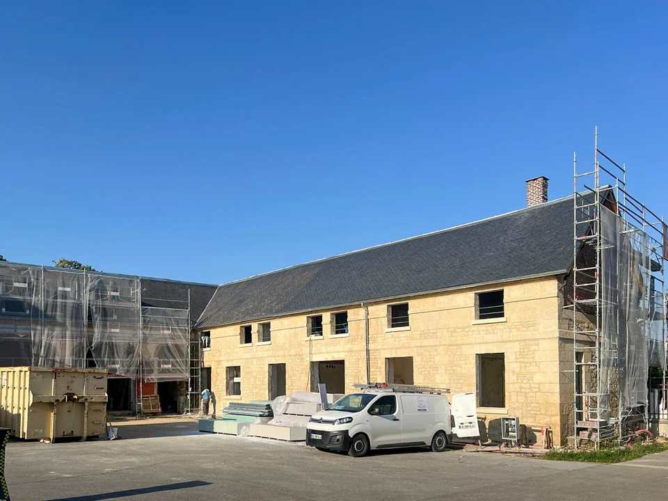 Travailleur qualifié de maçonnerie posant des briques dans un projet de construction sous la lumière du soleil sur un chantier de construction