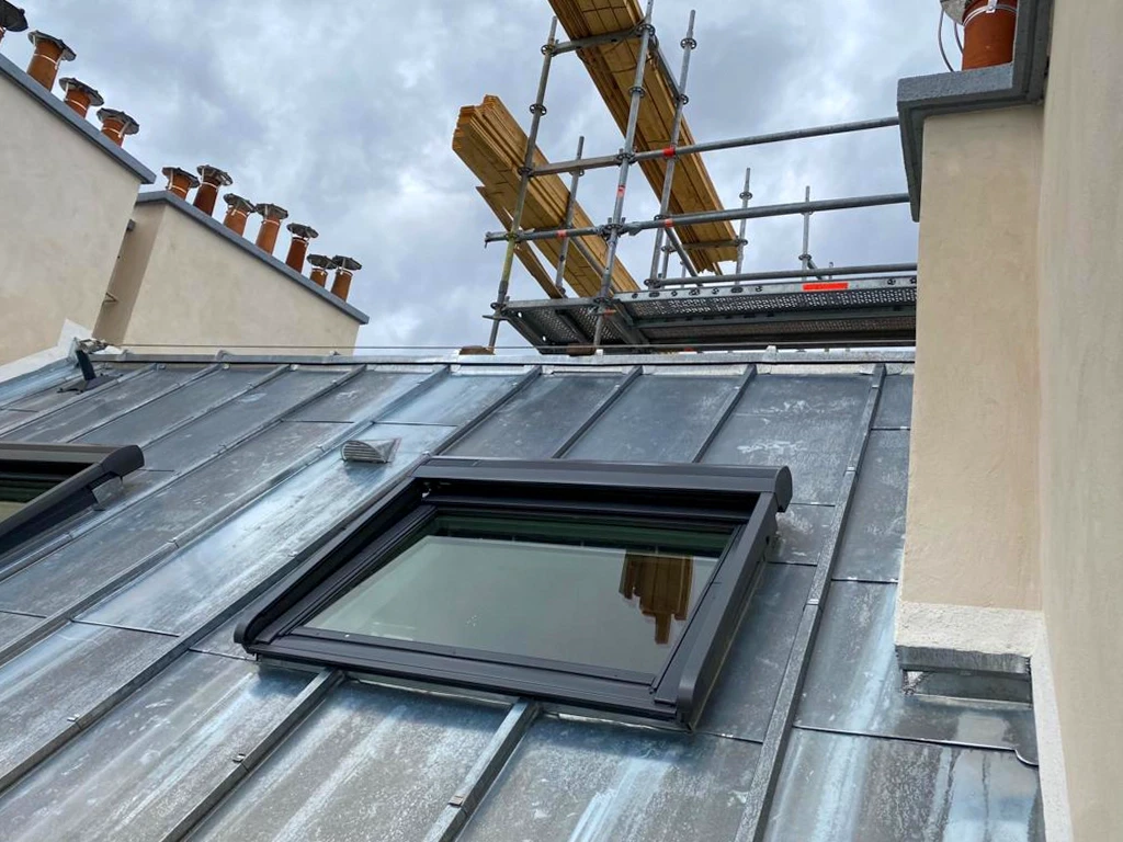 Chantier de rénovation de toiture en cours avec échafaudages métalliques sécurisés autour d'un bâtiment historique