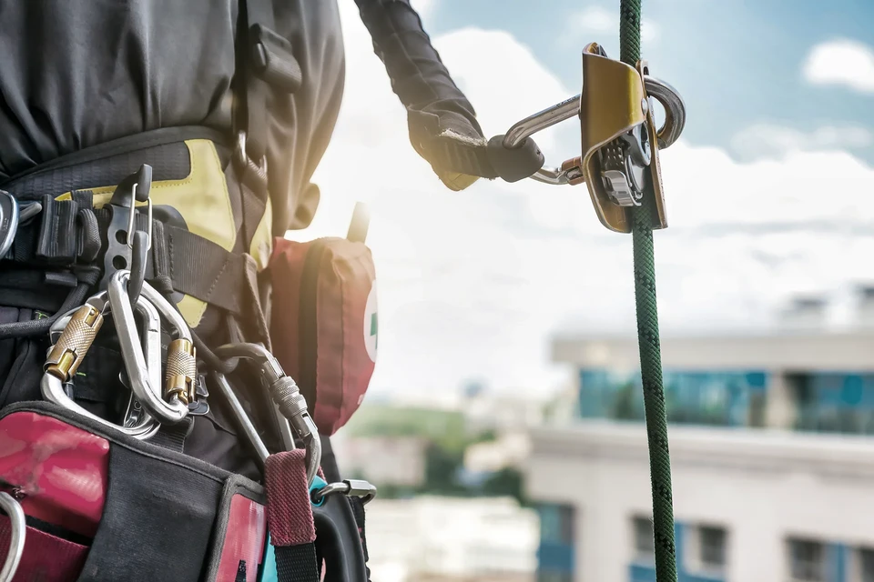 Chantier ext&eacute;rieur avec trois ouvriers &eacute;quip&eacute;s de harnais de s&eacute;curit&eacute; rouge travaillant sur &eacute;chafaudage m&eacute;tallique
